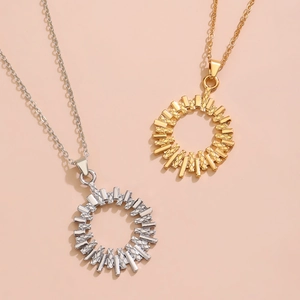 Flat lay of gold and silver sunburst necklaces with engraved bars on a peach background