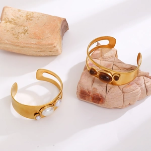 Detail of 18k gold plated stainless steel bangles with tiger eye stones and pearls