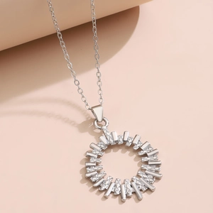 Detailed close-up of a silver sunburst pendant with geometric textures and a fine link chain