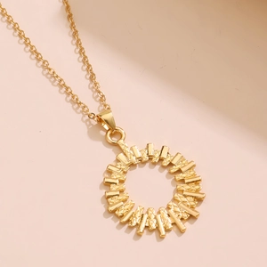 Macro detail of golden solar flower pendant with textured rectangular rays on O-chain necklace