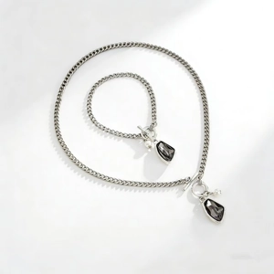 Dettaglio set collana e bracciale argento con cristalli scuri e chiusura a barra OT