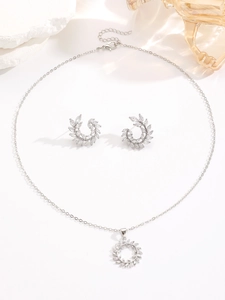 Close-up of luxury silver zircon necklace and earrings with olive leaf floral patterns