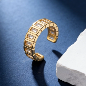 Macro detail of a golden open ring featuring rectangular cubic zirconia in a geometric setting