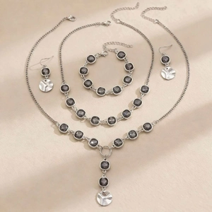 Dettaglio flat lay di un set di gioielli da 4 pezzi con cristalli grigi e catena argento
