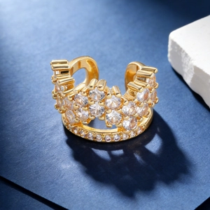 Macro detail of crown shaped gold ear cuff featuring sparkling white zircon stone inlay