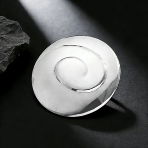Détail macro de la broche tourbillon en argent poli sur fond de roche noire