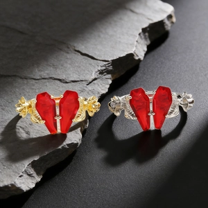 Gothic style rings with red coffin-shaped stones forming a heart on dark grey rock