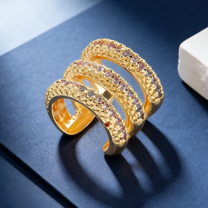 Detail of gold triple-band ring with inlaid purple, pink and clear cubic zirconia