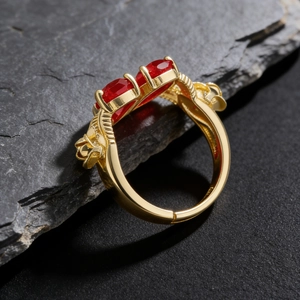 Close-up of gothic gold ring with double red stones on rugged dark stone texture