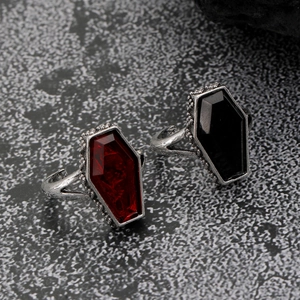 Detailed macro of gothic open rings with red and black coffin stones on grey rock