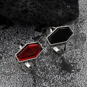 Detail of gothic rings featuring scarlet coffin gems and vintage metal roses on dark rock