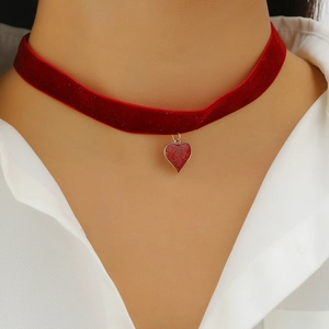 Close-up of red velvet choker featuring a shimmering glitter heart pendant on model
