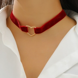Close-up of a red velvet choker necklace with a gold heart-shaped metal link