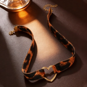 Detail of leopard print velvet choker with a gold heart pendant and adjustable clasp