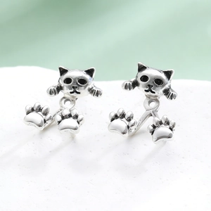 Detalle macro de pendientes de gato retro con acabado de plata vintage sobre base de piedra