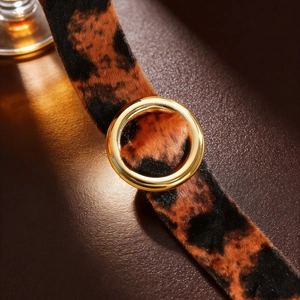 Detailed macro of leopard print velvet strap and polished gold circular metal buckle