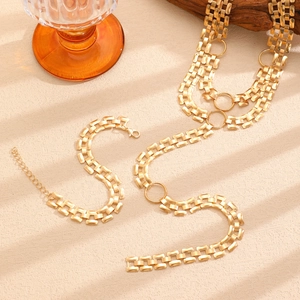 Detail of gold-plated rectangular links and round metal loops on a layered necklace