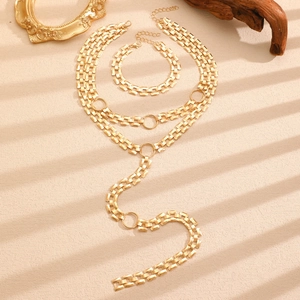 Detailed view of chunky gold layered necklaces and bracelet set with O-rings on textured surface