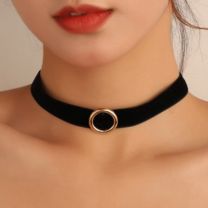 Detailed view of black velvet choker featuring a polished gold metal ring on a model