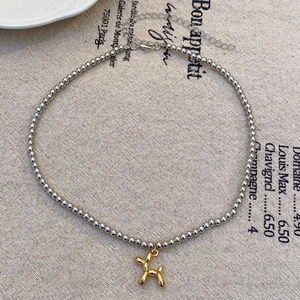 Dettaglio collana con perle d'argento e ciondolo a forma di cane palloncino dorato