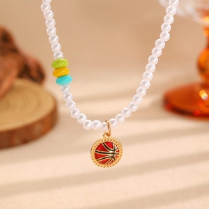 Gros plan d'un collier de perles avec un pendentif de basket rouge et noir aux bords dorés