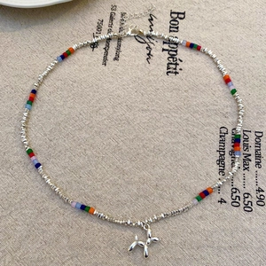 Dettaglio di una collana di perline multicolori con un ciondolo a forma di cane palloncino