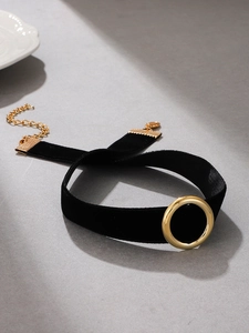 Close-up of black velvet choker with gold ring pendant and adjustable lobster clasp