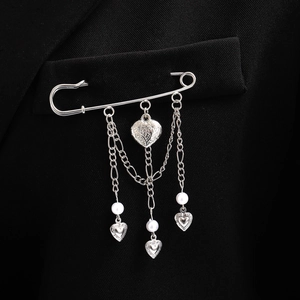 Détail de la broche cœur à pompon argenté avec perles sur le revers d'un costume noir