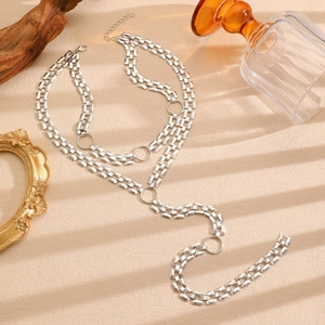 Detail view of silver multi-layer body chain with rectangular links on beige background