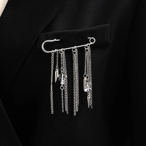 Détail d'une broche à franges argentée avec chaînes et cristaux sur un costume noir