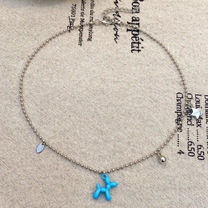 Dettaglio ravvicinato di un ciondolo a forma di cane palloncino blu su collana argento