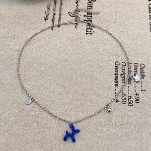 Dettaglio collana di perle con cane palloncino blu, sfera d'argento e stelle
