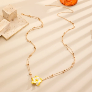 Close-up of gold beaded waist chain with plumeria flower under shutter shadow
