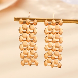 Detail of gold fringe earrings featuring polished metal discs in a layered chain design