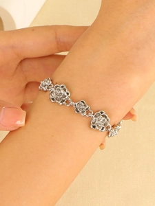 Detail of silver rose flower link bracelet worn on wrist with vintage floral design