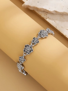 Macro detail of vintage silver rose link bracelet on stone and cream display stand