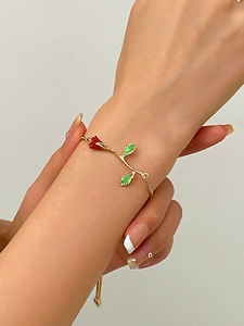 Detail of elegant gold rose bracelet with red enamel bud and green leaves on wrist