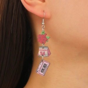 Gros plan de boucles d'oreilles pendantes avec rose et cassette portées par le mannequin