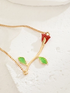 Detail of elegant gold box chain necklace with red rose pendant and green leaves