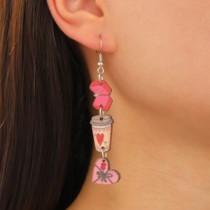 Gros plan de boucles d'oreilles tasse à café rose et cœur sur mannequin avec pompons