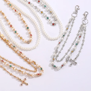 Dettaglio della catena in perle con ciondoli in strass colorati e pendente a croce