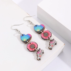 Détail de boucles d'oreilles en bois avec fleurs roses et cœurs bleus sur fond blanc
