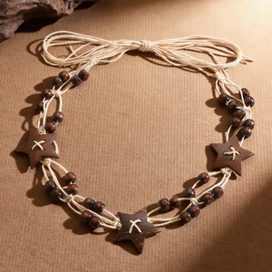Bohemian braided waist chain belt with wooden beads and star pendants on textured background