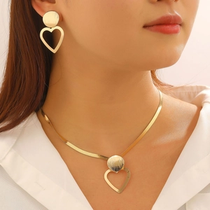 Detail of elegant gold heart necklace and earrings set with brushed texture on female model
