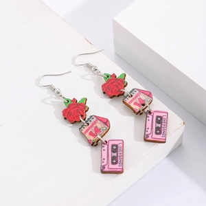 Détail de boucles d'oreilles en bois avec cœur rose et cassette LOVE SONGS sur présentoir
