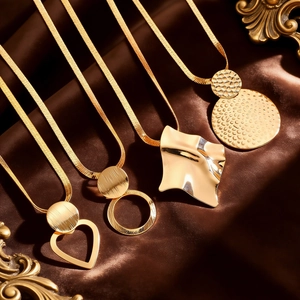 Detail of four gold geometric pendants including heart and circle on brown silk