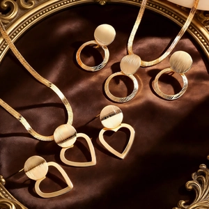 Detail of gold heart and circle geometric jewelry set on elegant brown silk fabric background
