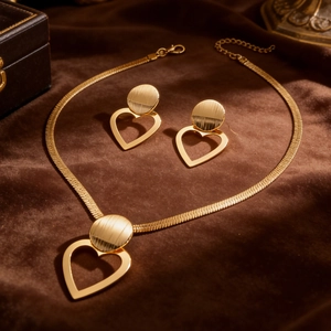 Detail of gold heart pendant necklace and earrings set on premium brown velvet display