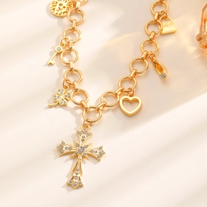 Collana con ciondoli dorati a forma di croce, cuore e quadrifoglio a catena