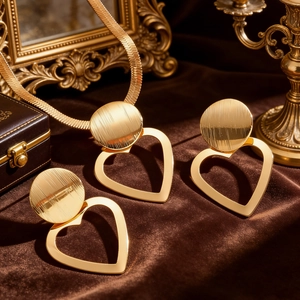 Elegant gold-tone heart and circle jewelry set with necklace and stud earrings on velvet